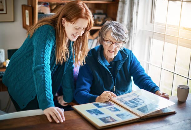 Grand-mère et petite-fille regardant un album photos — pourquoi faire sa généalogie en famille
