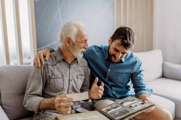 Père et fils regardant un album photo de famille - transmission mémorielle